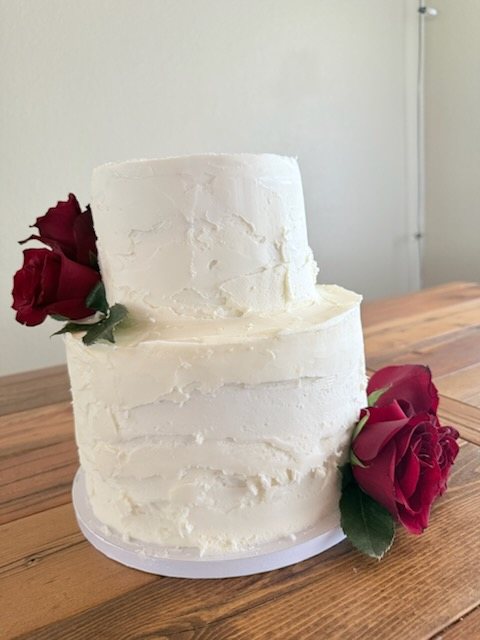 Two-tier white buttercream cake with red roses